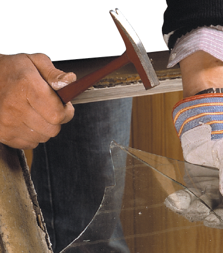 Enlever les débris de vitre avec un marteau de vitrier en portant de gros gants de bricolage - Coll. C.P.