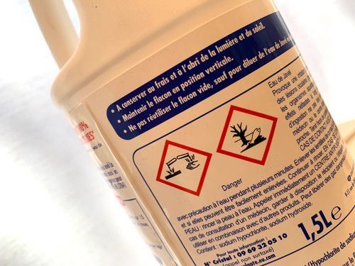 Les dangers liés à l'eau de Javel sont clairement exprimés sur l'étiquetage des bouteilles : corrosif (à gauche) et dangereux pour l'environnement (à droite) - coll. CP